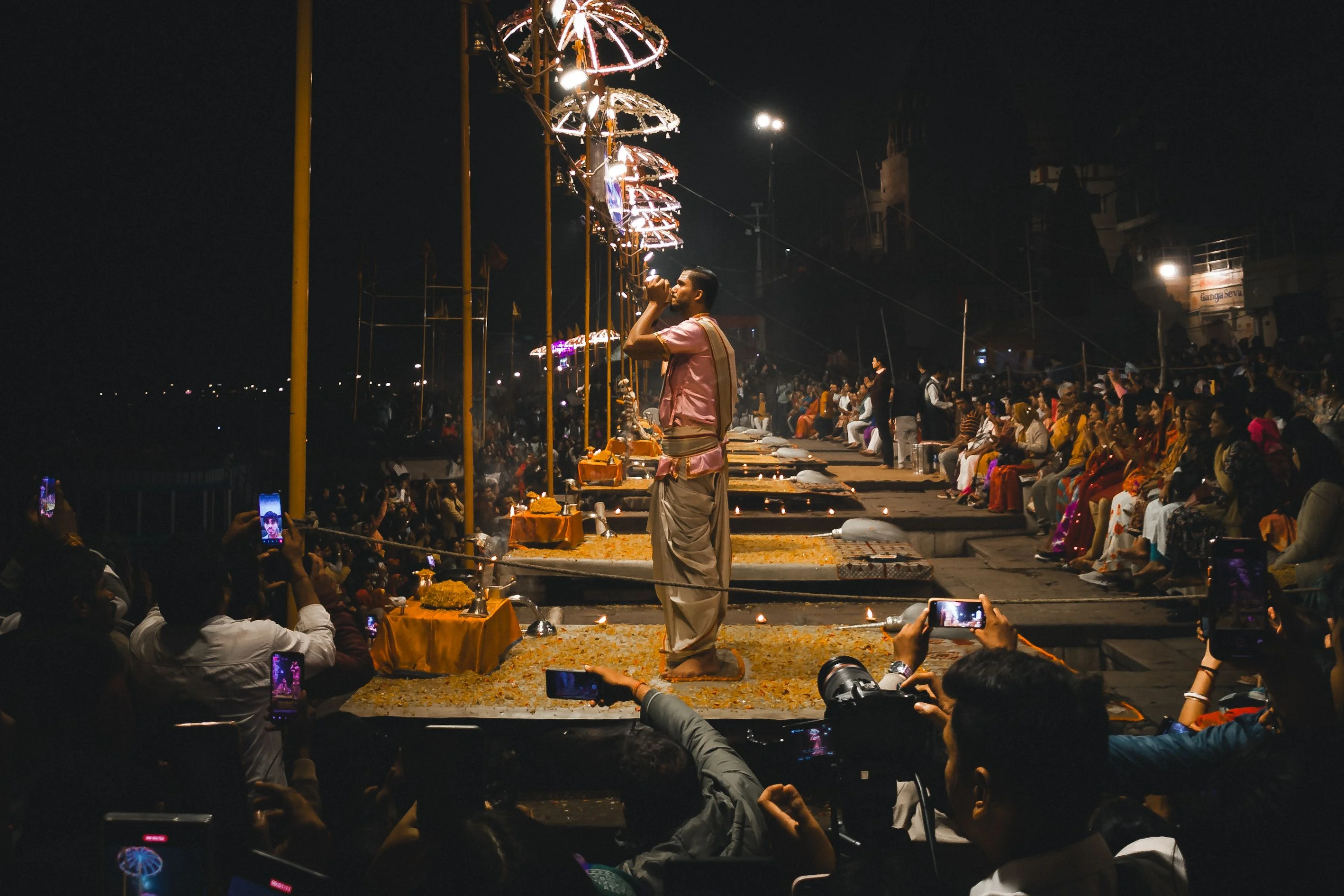 A priest performs the evening Ganga Aarti on the ghats of Varanasi, surrounded by onlookers