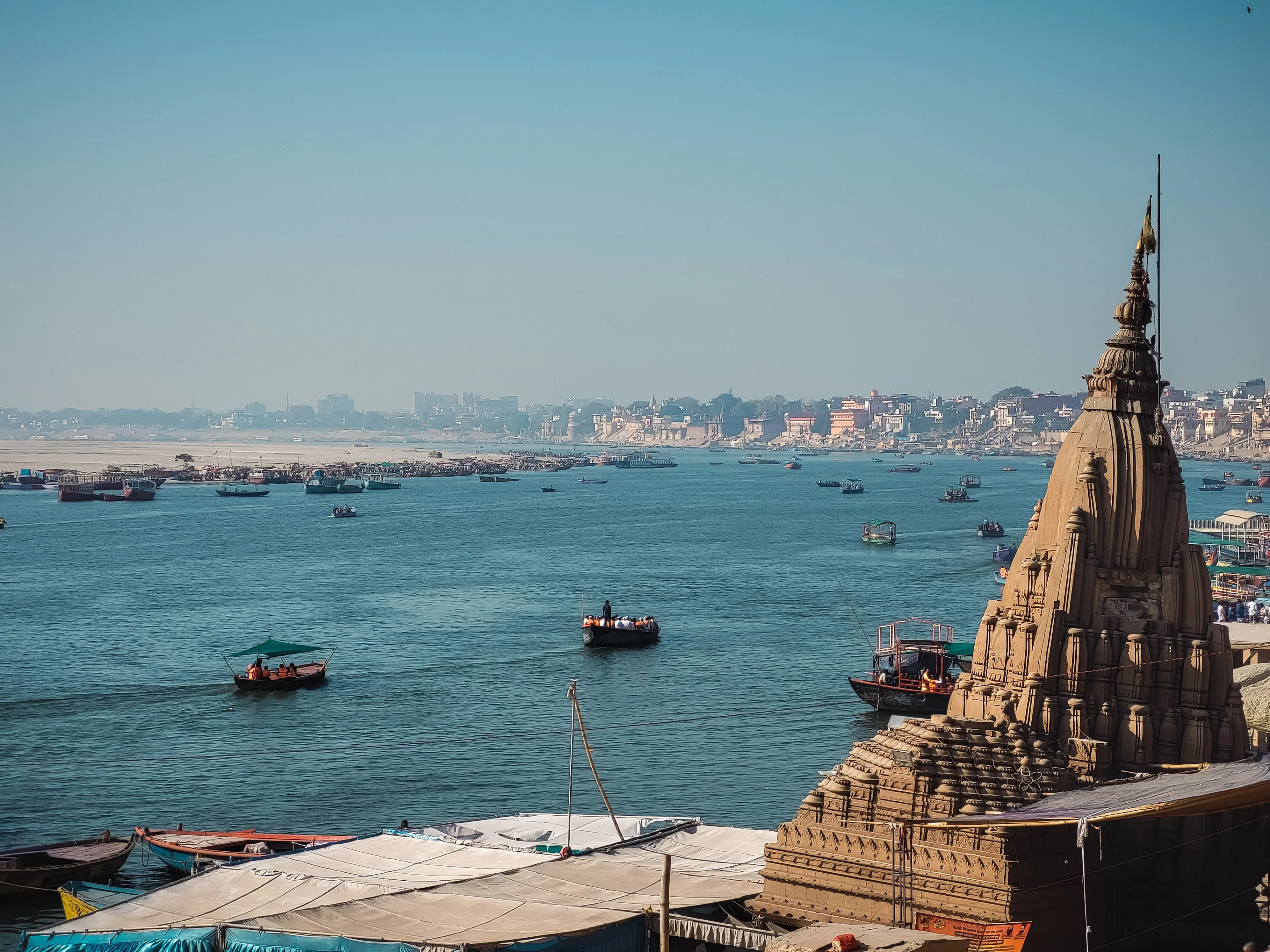 Boats on the Ganges river at Varanasi with the city skyline and a riverside temple in view